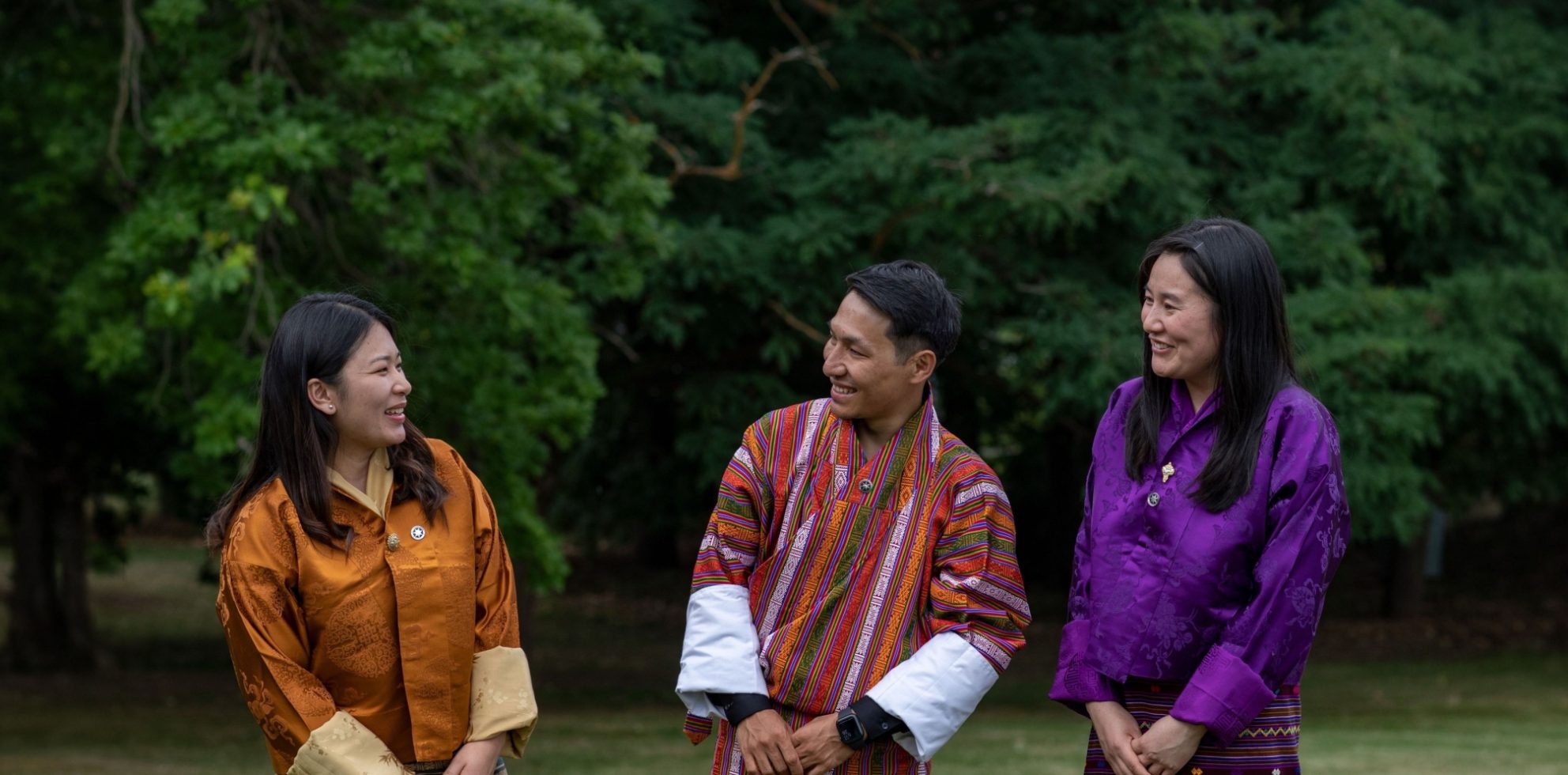 Three Bhutanese Australia Awards alumni talking outdoors in traditional dress